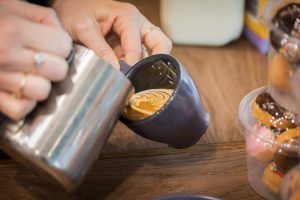 milk being poured into coffee cup